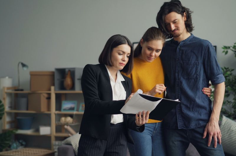 Consultora apresenta documentos a um casal durante uma reunião, exemplificando como as vendas consultivas ajudam a compreender as necessidades do cliente e oferecer soluções personalizadas com mais confiança e transparência.