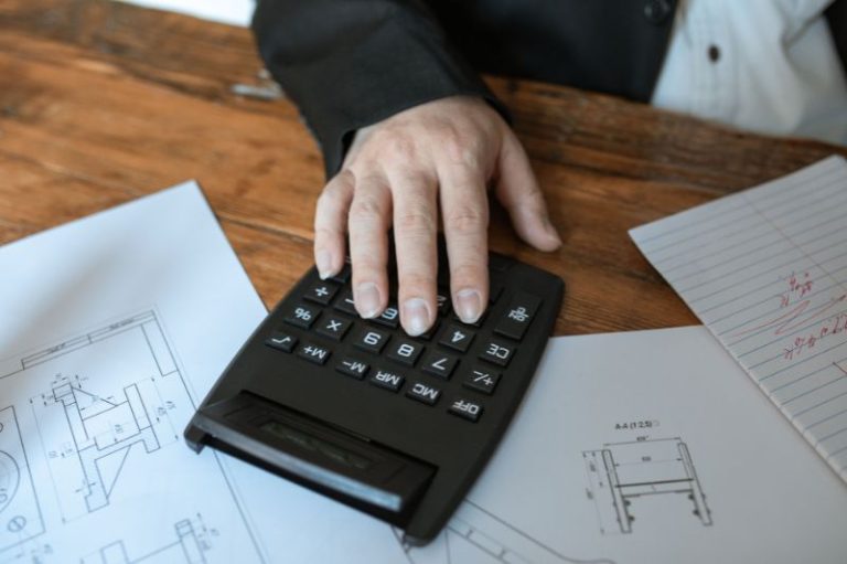 Pessoa utilizando uma calculadora sobre documentos contábeis, representando a atuação estratégica do gestor contábil do futuro na busca por eficiência e organização financeira.